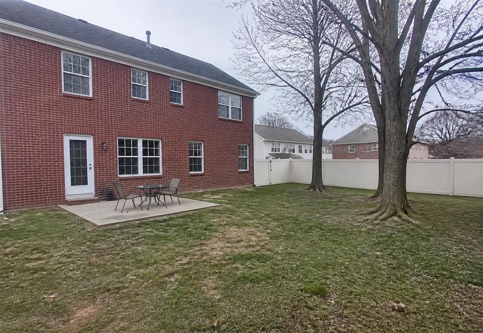 Westfield Indiana estate backyard before renovation — original lawn, patio, and mature oaks